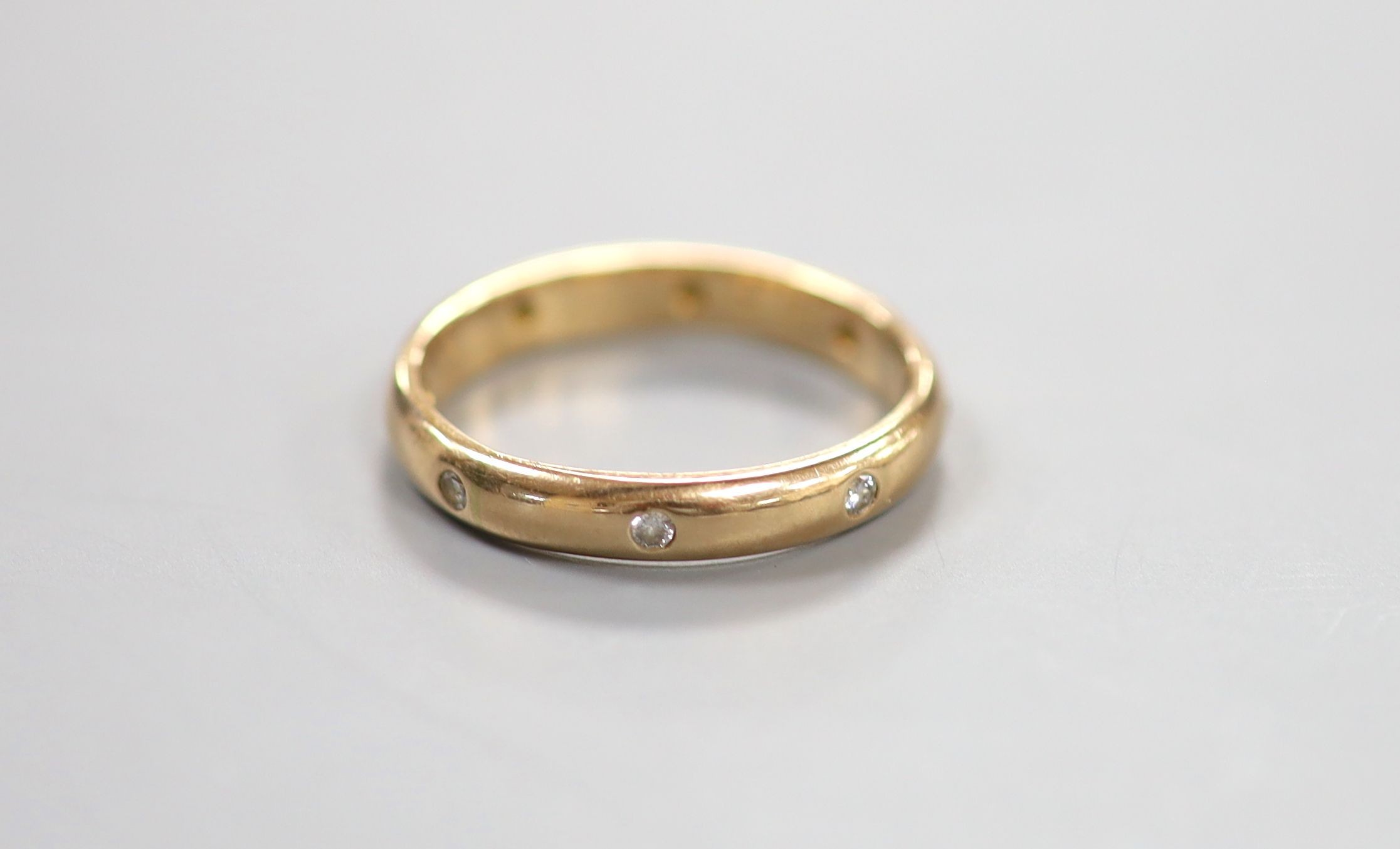A modern 14k and gypsy set eight stone diamond eternity ring, size R/S, gross 4.3 grams.